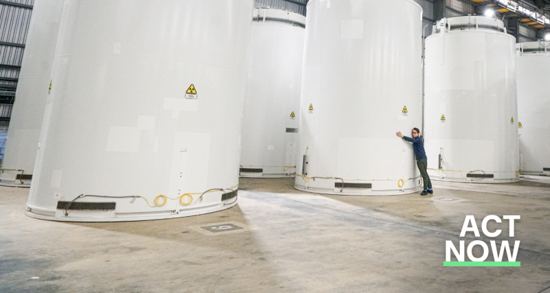 The dry used fuel store at the Sizewell B nuclear plant. The picture shows a large room containing white cylinders. To one side, WePlanet's head of campaigns, Joel Scott-Halkes, is visible hugging one of the cylinders.