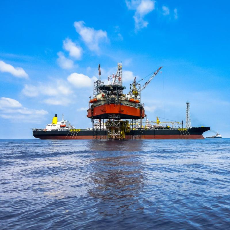 Bild von einer Plattform für Gasbohrungen auf offener See mit einem Schiff, welches das gewonnene Gas abholt